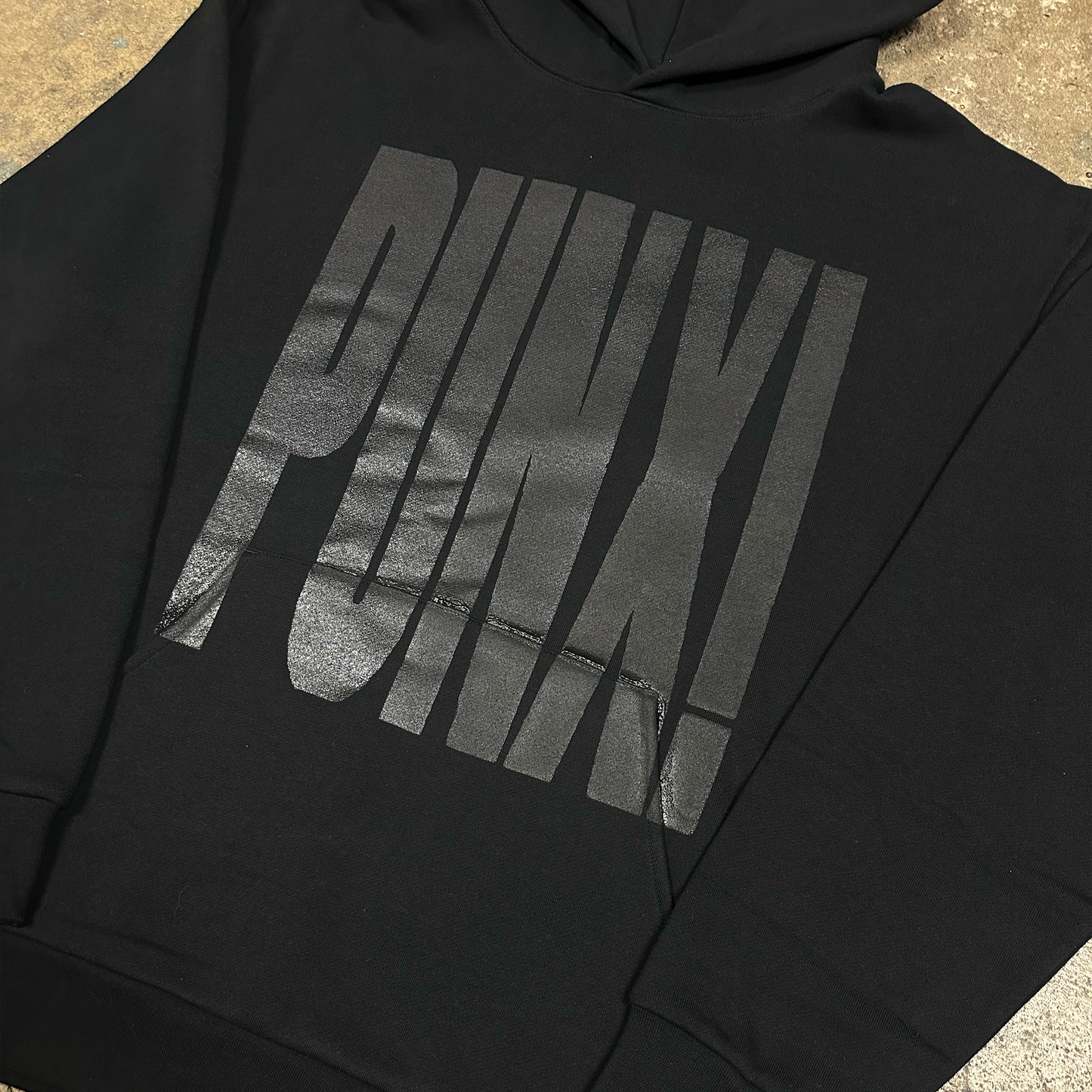 Black hoodie with 'PUNX' logo on a concrete surface