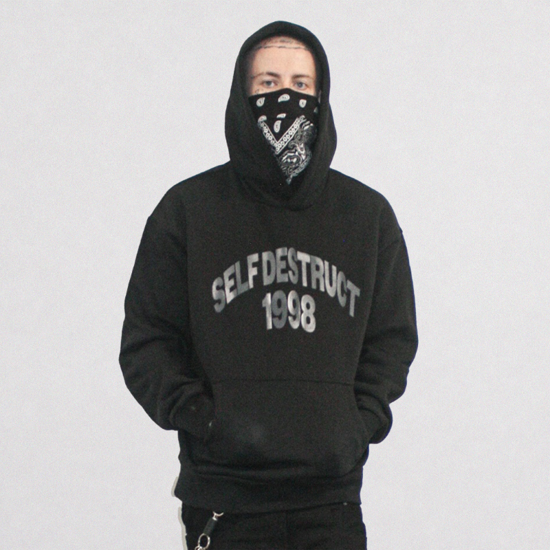 A person wearing a black pullover hoodie with 'SELF DESTRUCT 1988' printed in gray on the chest, paired with a black bandana covering their face, set against a plain light gray background.