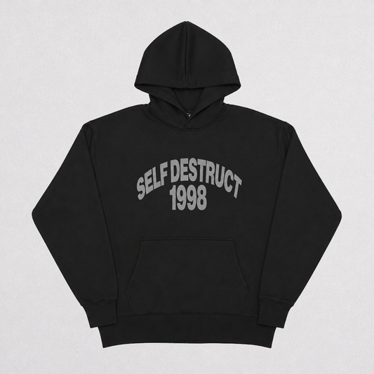 A black pullover hoodie with 'SELF DESTRUCT 1998' printed in gray arched text across the chest, displayed flat against a light gray background.
